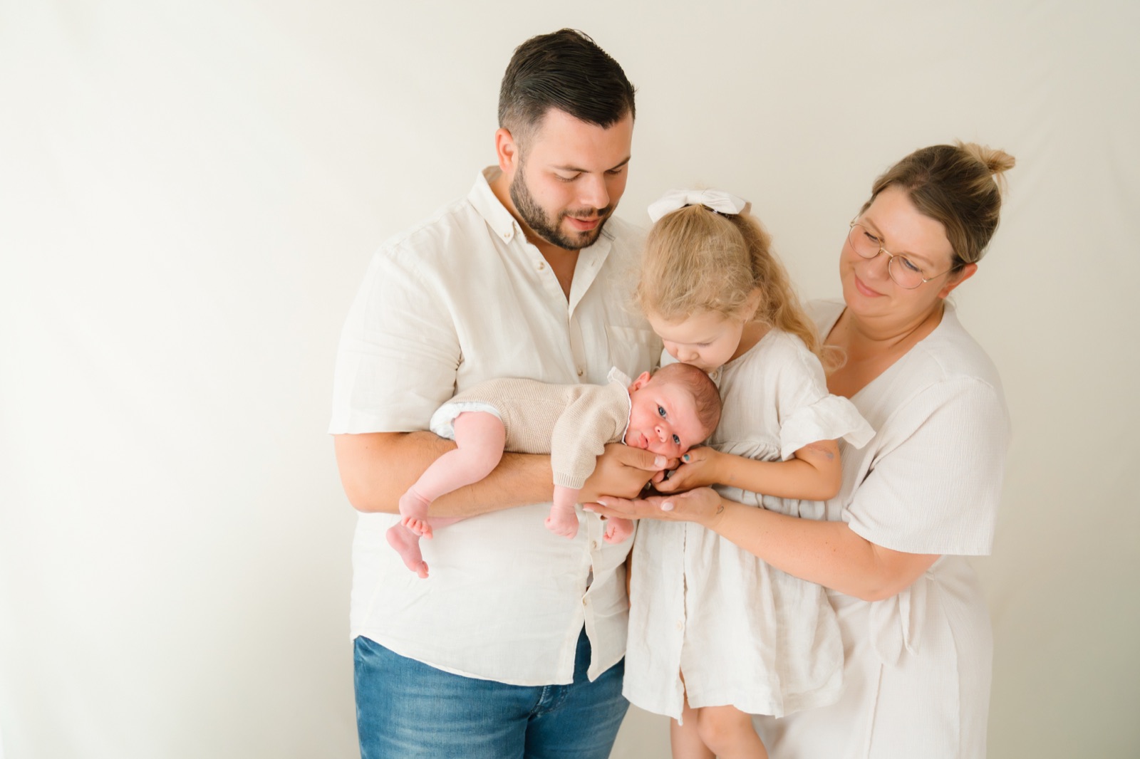 Grouss Schwëster gëtt dem Neigebuerenen e Kuss, Papa a Mama halen hir Kanner, Newborn Shooting zu Lëtzebuerg